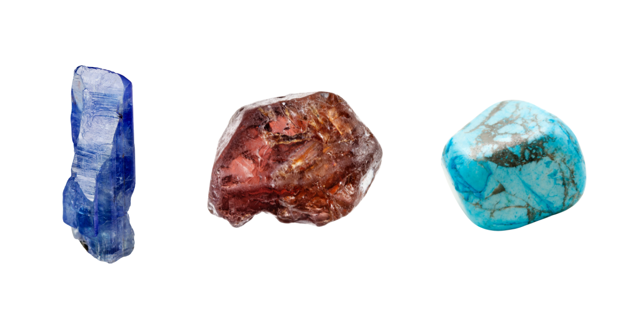 Three raw December birthstones on white background, including blue-violet tanzanite, reddish-brown zircon, and blue-green turquoise gemstones.
