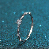 0.06 CTW DEW round moissanite decorative ring in platinum plated sterling silver with oval connected band and prong-set side stones