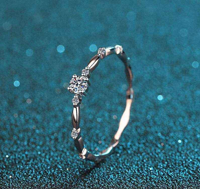 0.06 CTW DEW round moissanite decorative ring in platinum plated sterling silver with oval connected band and prong-set side stones