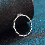 0.06 CTW DEW round moissanite decorative ring in platinum plated sterling silver with oval patterned band and prong-set side gems