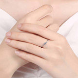 0.06 CTW DEW round brilliant moissanite ring in platinum plated sterling silver on hand