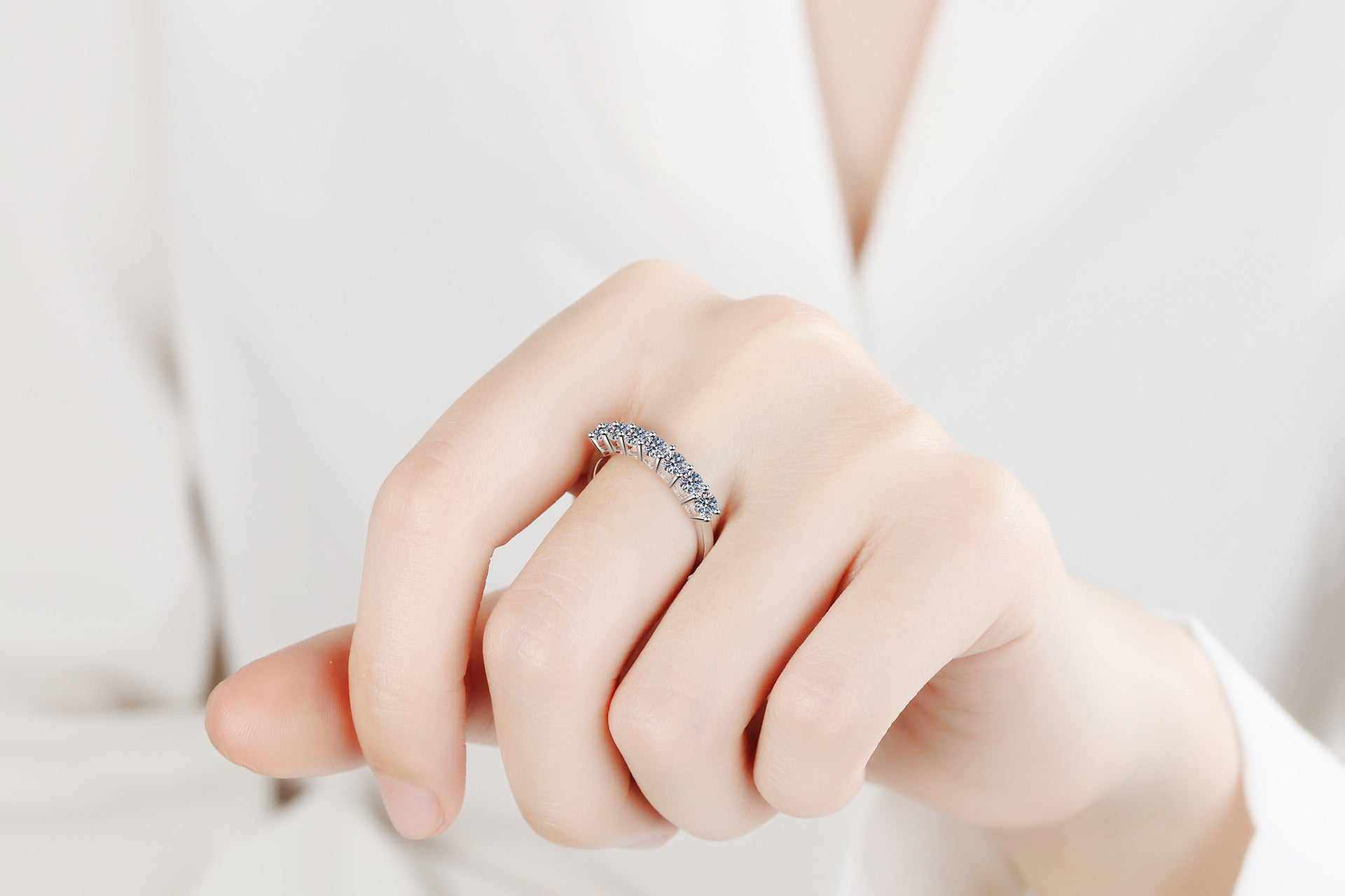 0.7 CTW DEW seven-stone round moissanite semi-eternity band in platinum plated sterling silver on hand