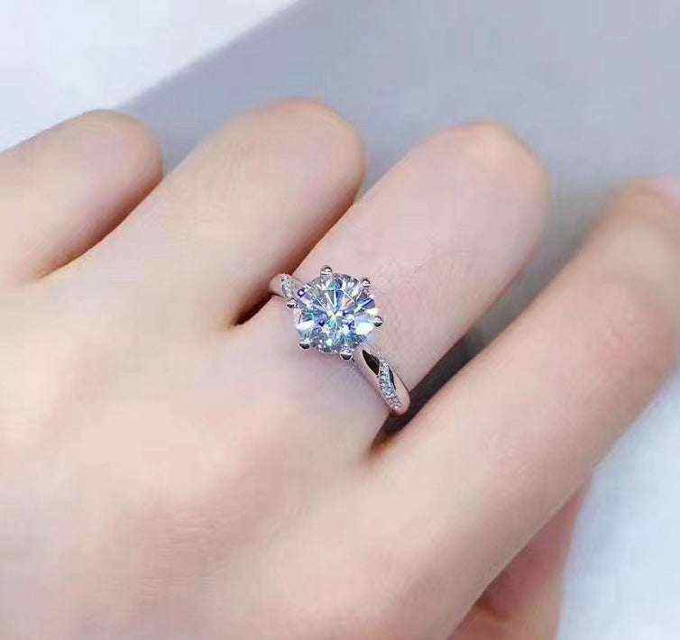 0.8 carat colorless round brilliant cut moissanite solitaire engagement ring in sterling silver with pave set accent stones on hand