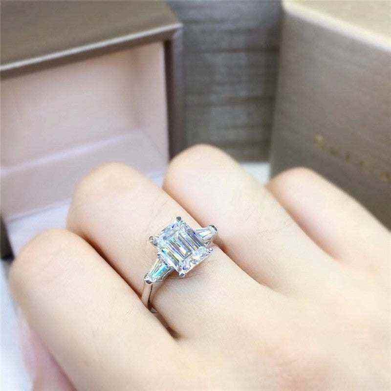 1.8 CTW DEW emerald cut colorless moissanite three stone engagement ring with tapered baguette accents in 18K gold plated sterling silver