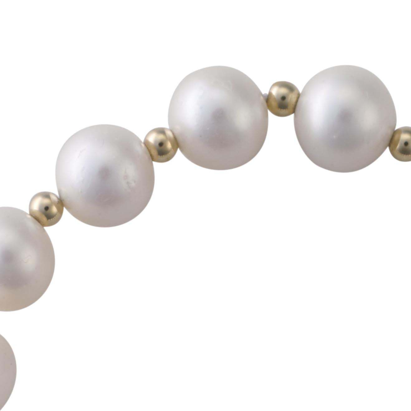Close-up of white freshwater cultured pearls and 9k gold beads on a stretch bracelet