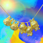 24K gold Labubu-inspired doll-head pendant necklace with sparkling moissanite stones on colorful background