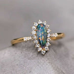 18K yellow gold engagement ring with pear-shaped Australian black opal surrounded by halo diamonds
