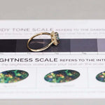 18K yellow gold Australian black opal halo diamond engagement ring on body tone scale with bright green and blue reflections