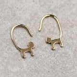18K yellow gold cat tail hook earrings in a minimalist design on a textured surface