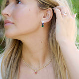 Hydrangea Earrings featuring pear-shaped lab-grown diamonds, natural iolite, and lab-grown emeralds in 14k gold worn by a woman