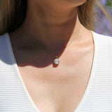 14K yellow gold oval moissanite pendant with 4 natural alexandrite stones worn on a woman in a white sleeveless top, vintage inspired mirror style necklace