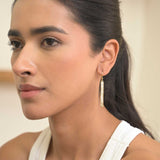 Close-up of a woman wearing Madeline Gold Vermeil Earrings with long, dangling design and pave diamond accents.