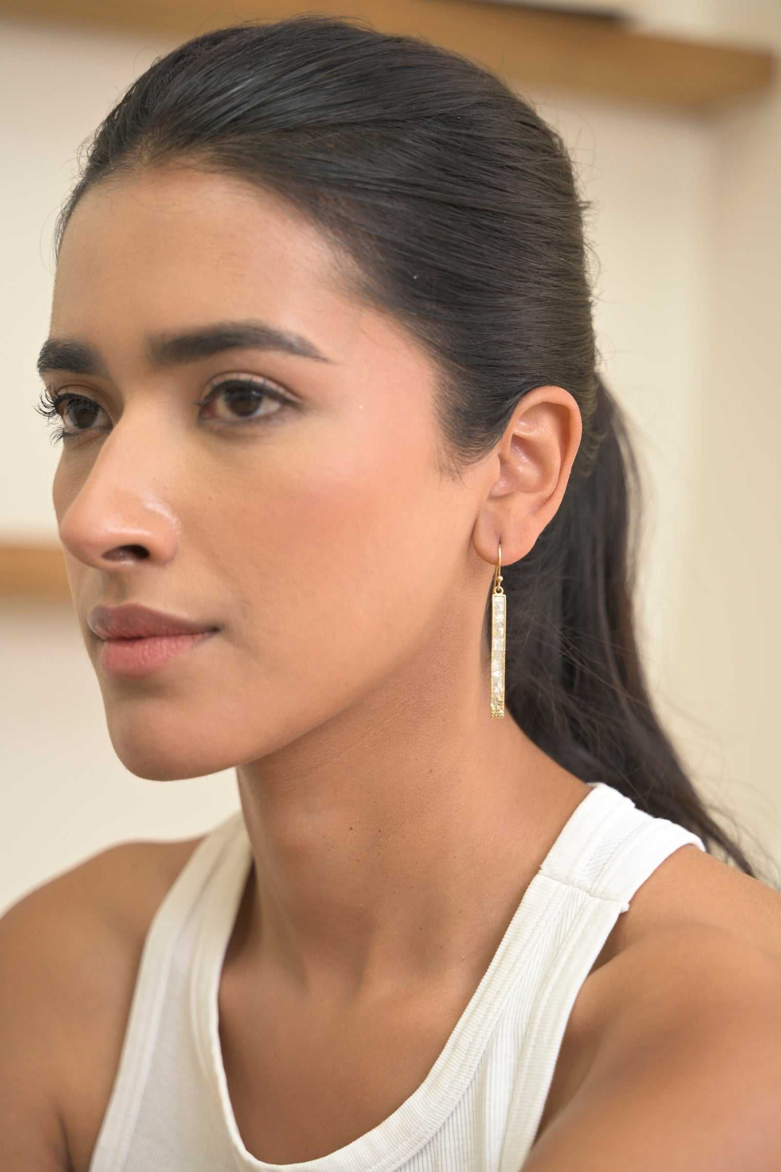 Close-up of a woman wearing Madeline Gold Vermeil Earrings with long, dangling design and pave diamond accents.