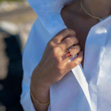 Boston Red Ring featuring 14k gold and cushion cut lab-grown ruby worn on finger with white blouse background