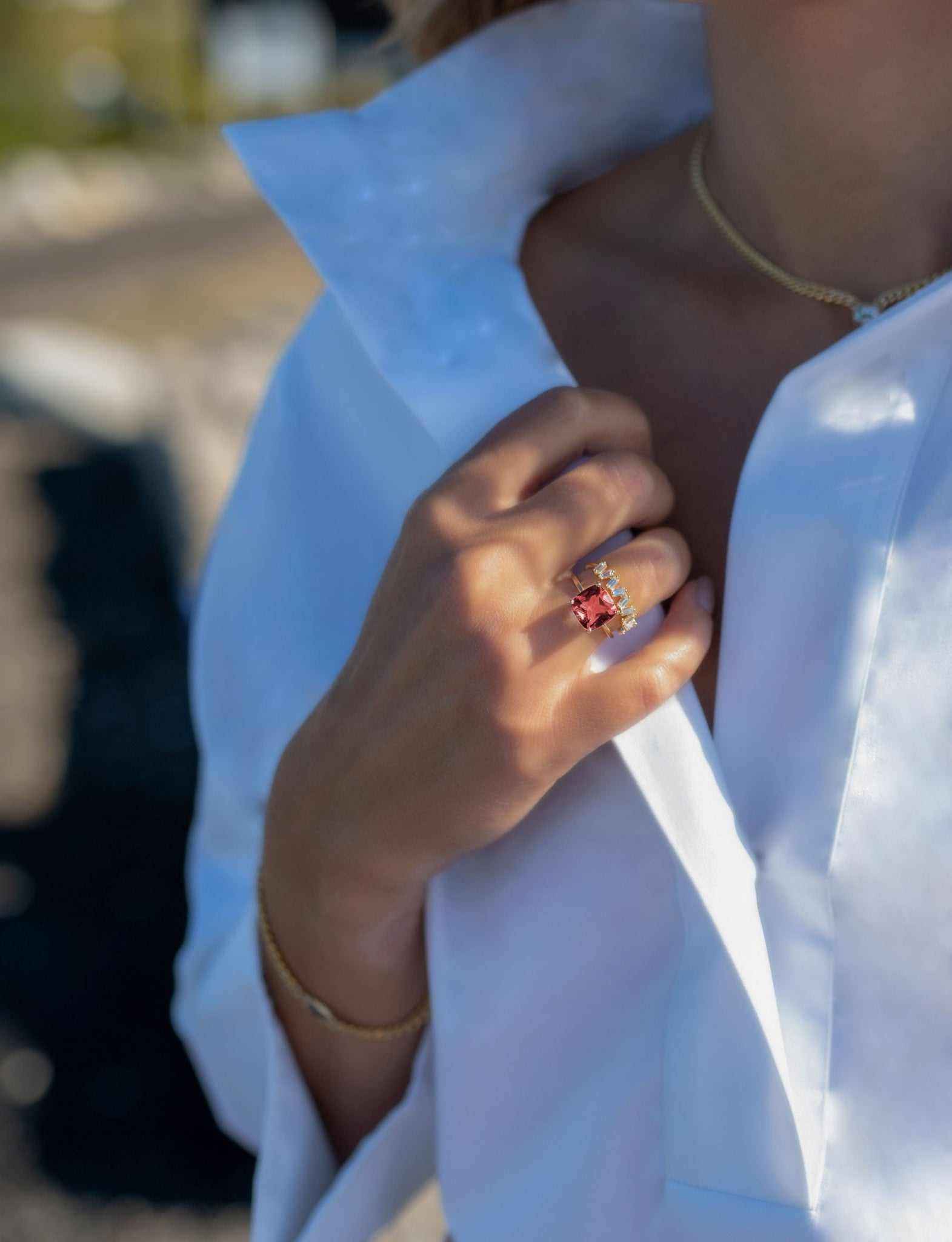 Boston Red Ring featuring 14k gold and cushion cut lab-grown ruby worn on finger with white blouse background