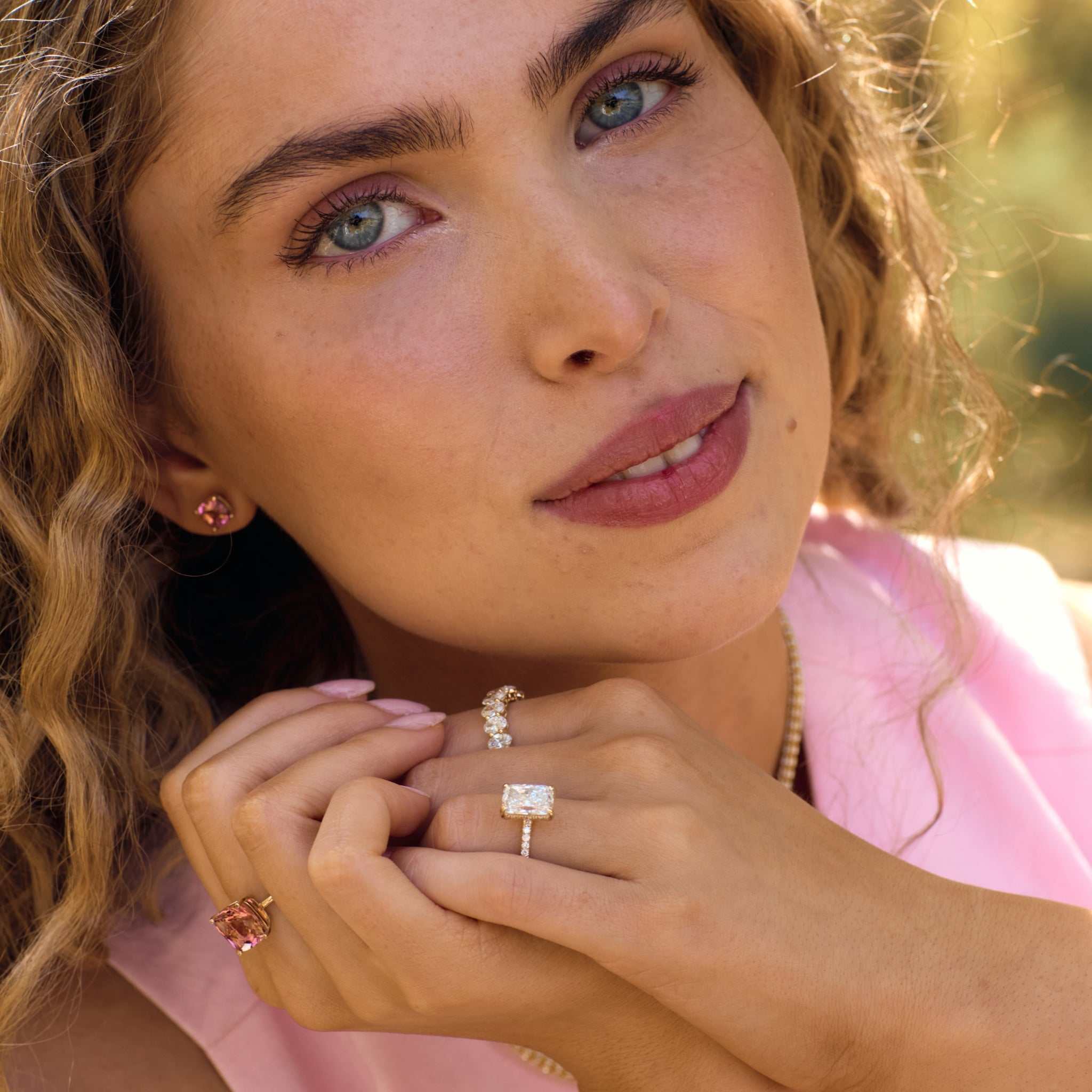 Close-up of woman wearing Nantucket Red pink tourmaline cushion-cut stud earrings with 14k yellow gold mounts.