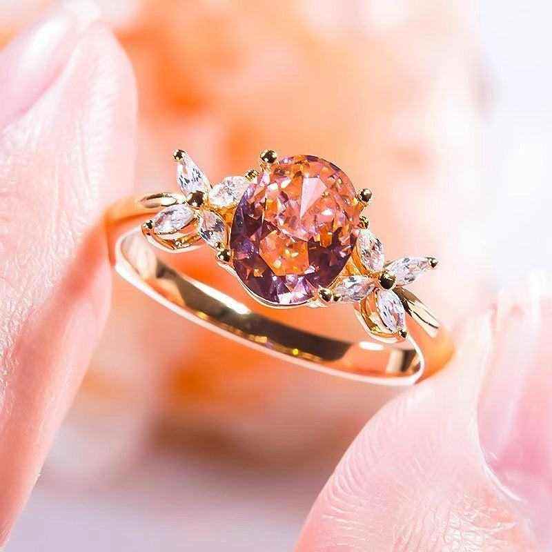 Oval cut pink moissanite engagement ring with three stones and four leaf flower accents in 18K rose gold plated sterling silver