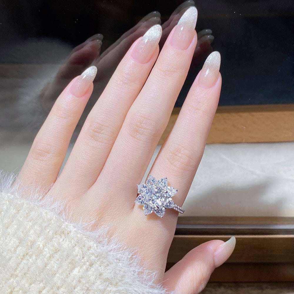 2.4 CTW DEW cushion cut moissanite sunflower halo engagement ring in sterling silver worn on finger