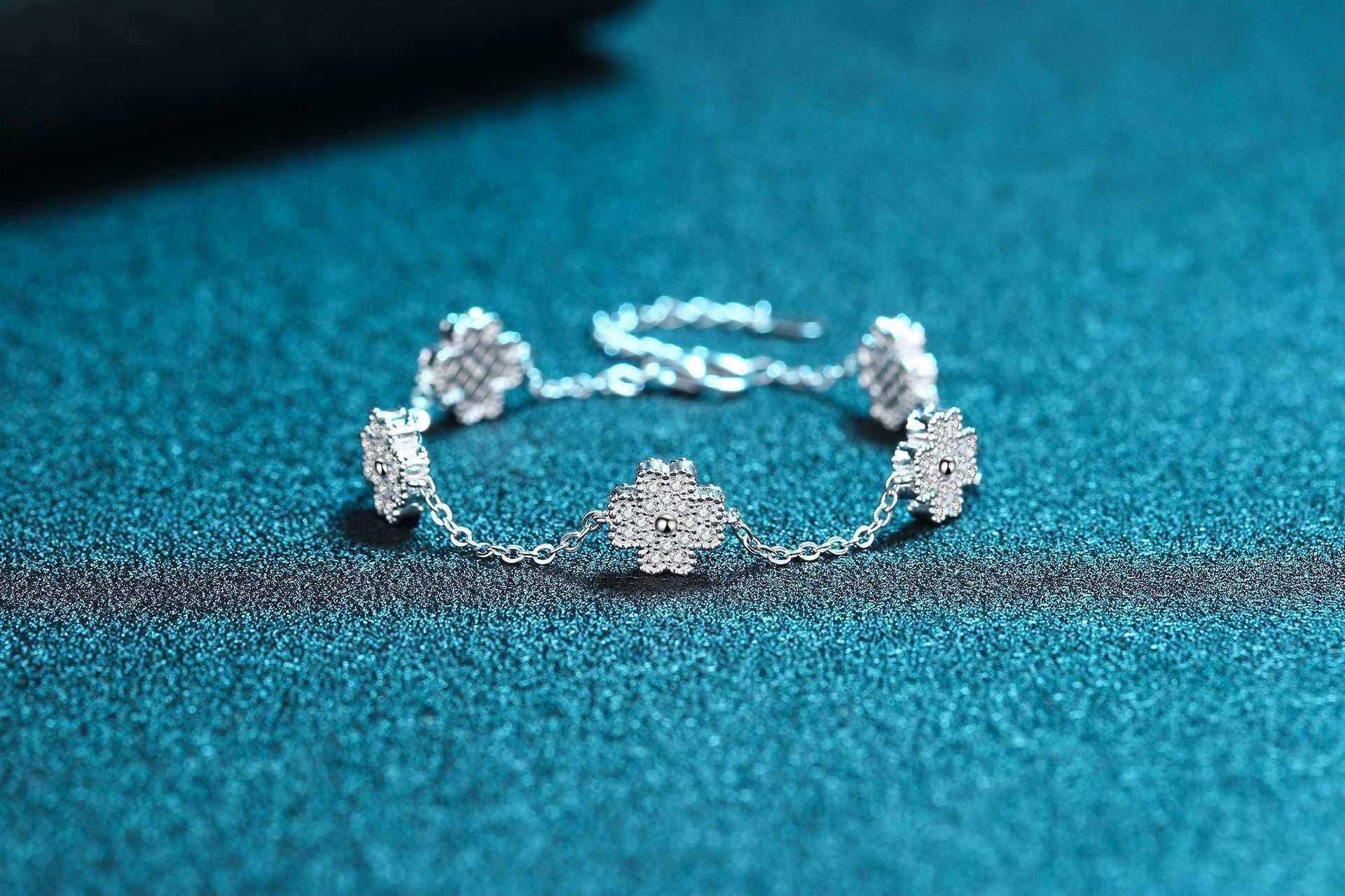 Adjustable 925 sterling silver bracelet with five colorless melee moissanite lucky clover freesia flower charms totaling 0.64 CTW DEW on a rolo chain