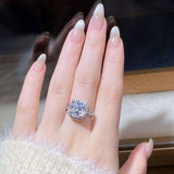 5 CTW colorless cushion cut crushed ice moissanite engagement ring in sterling silver pavé halo setting on hand