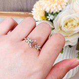 Oval cut pink moissanite three-stone engagement ring with flower accents in 18K rose gold plated sterling silver on hand