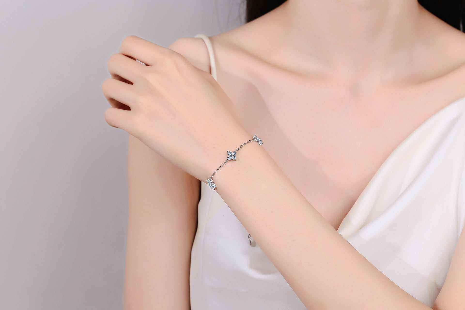 Adjustable sterling silver bracelet with five colorless four-leaf flower moissanite stations on rolo chain