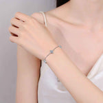 Adjustable sterling silver bracelet with five colorless four-leaf flower moissanite stations on rolo chain