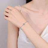 Adjustable sterling silver bracelet with five colorless four-leaf flower moissanite stations on rolo chain