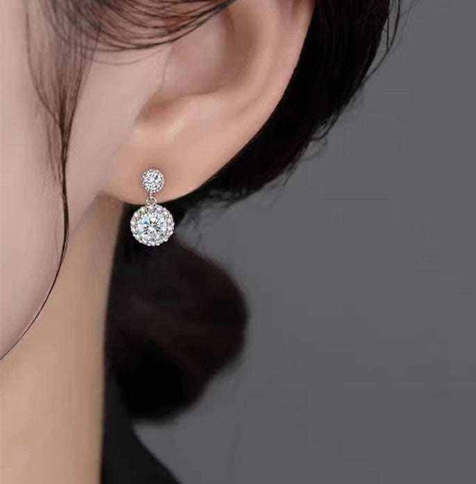 Close-up of ear wearing 1 CTW DEW colorless round cut moissanite halo drop earring in 925 sterling silver with push back stud
