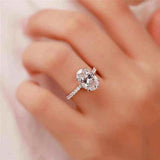 2.1 CTW DEW colorless oval brilliant cut moissanite engagement ring in sterling silver with pavé outline on finger