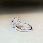 Sterling silver pavé halo engagement ring with 5 CTW colorless cushion cut moissanite and cubic zirconia accents