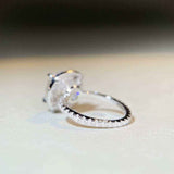 Sterling silver pavé halo engagement ring with 5 CTW colorless cushion cut moissanite and cubic zirconia accents