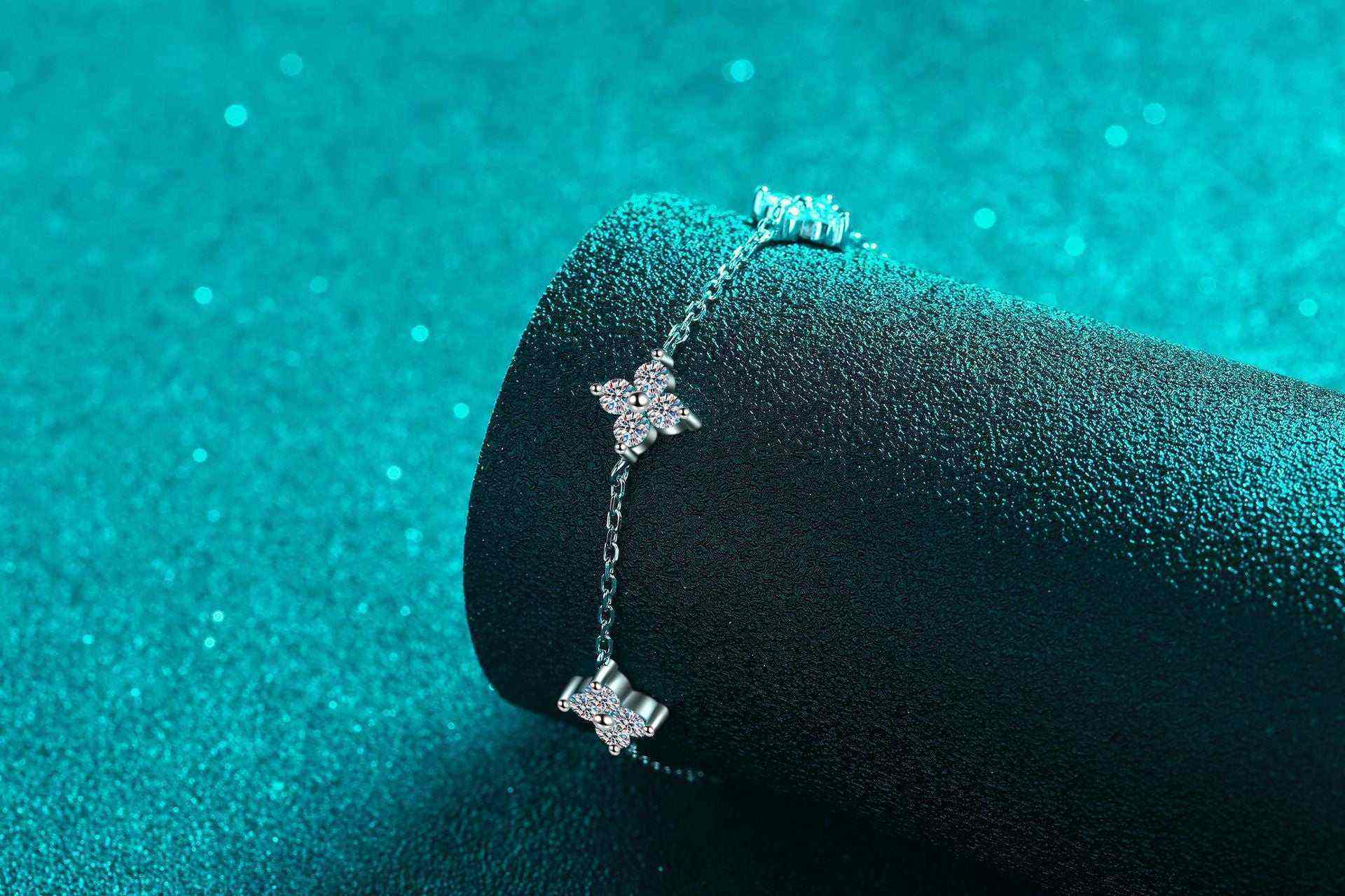 Adjustable sterling silver bracelet with five colorless moissanite four-leaf flower charms on a rolo chain