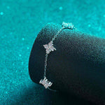 Adjustable sterling silver bracelet with five colorless moissanite four-leaf flower charms on a rolo chain