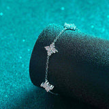 Adjustable sterling silver bracelet with five colorless moissanite four-leaf flower charms on a rolo chain