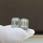 Pair of 1.05 CTW DEW emerald cut rectangular colorless moissanite halo stud earrings in 925 sterling silver with push back closures