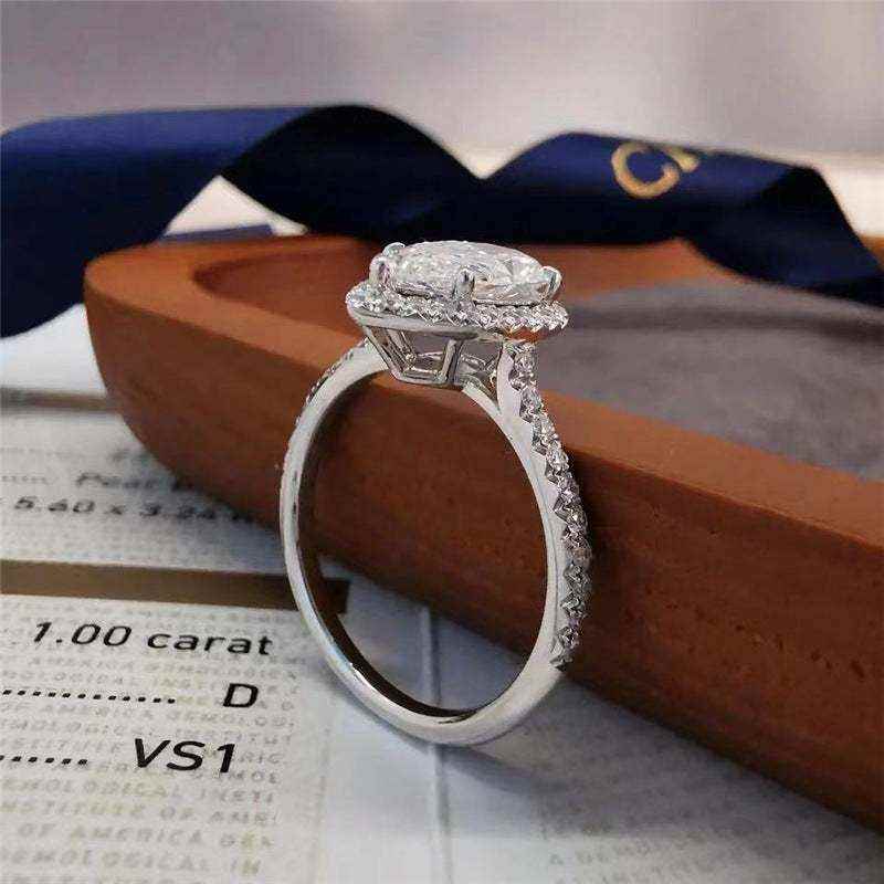 Pear cut colorless moissanite engagement ring with sterling silver pavé halo and outlined shank