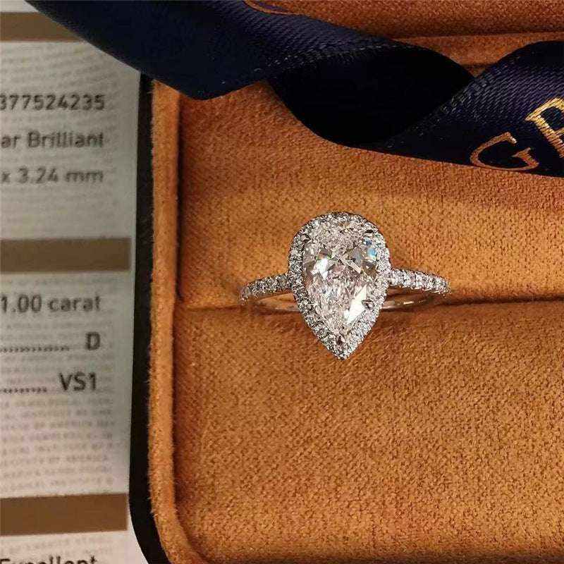 Pear cut colorless moissanite engagement ring with sterling silver pavé halo and outline setting in a jewelry box