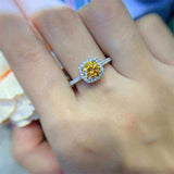 1 CTW DEW round brilliant cut yellow moissanite sterling silver cushion outline pavé halo engagement ring on hand