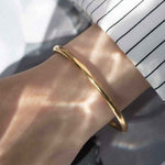 18K yellow gold matte bangle bracelet on wrist in natural light</|endoftext|>