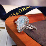 Pear cut colorless moissanite engagement ring with sterling silver pavé halo and outline setting