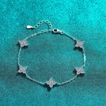 Adjustable sterling silver bracelet with five colorless four-leaf flower moissanite stations on rolo chain