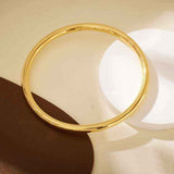 18K yellow gold round matte bangle bracelet with minimalist design on neutral background