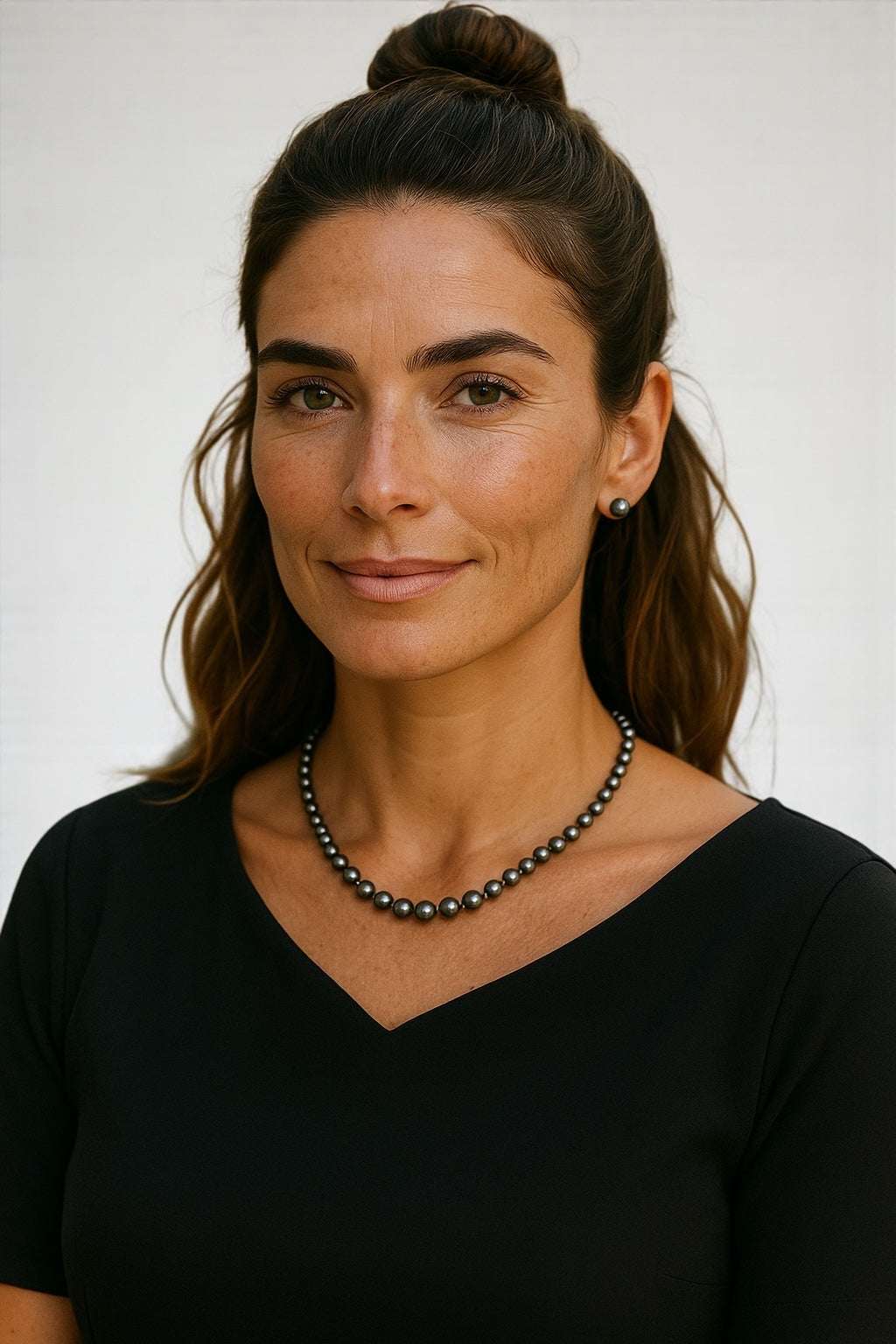 Elegant black freshwater pearl strand necklace worn by woman with black top and simple earrings