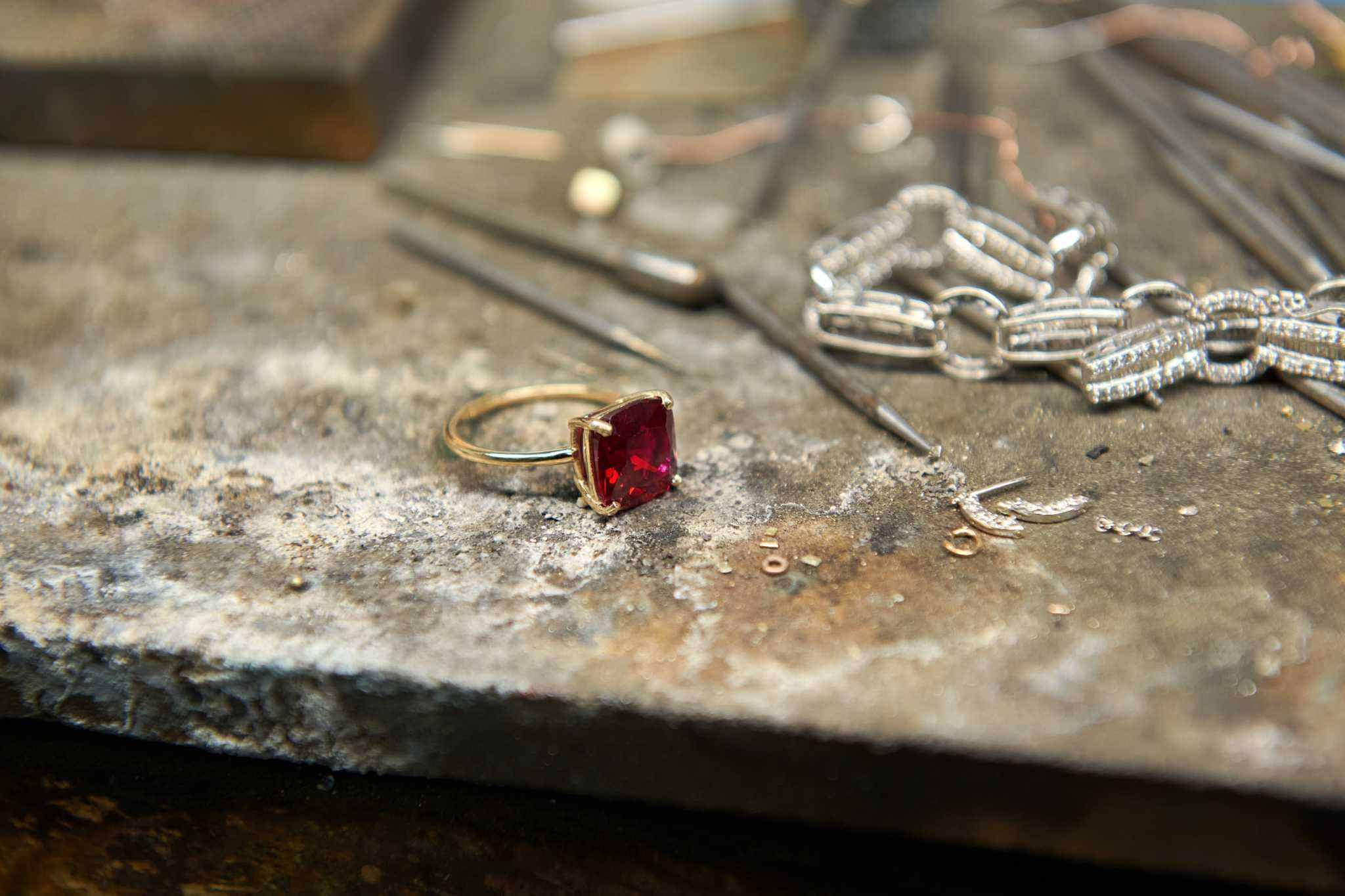 Boston Red Ring featuring a 10x10mm cushion cut lab-grown ruby set in 14k gold on a jeweler's workbench