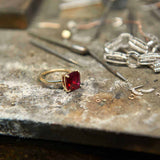 Boston Red Ring featuring a 10x10mm cushion cut lab-grown ruby set in 14k gold on a jeweler's workbench