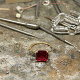 Boston Red Ring featuring a 14k gold band and a cushion-cut lab-grown ruby centerpiece on a jeweler's workbench