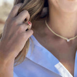 Close-up of a woman wearing the Boston Red Ring with a cushion-cut lab-grown ruby set in 14k gold, styled with a white blouse and gold necklace.