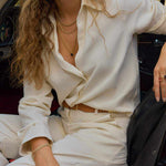 Woman wearing Cape Cod Horizon Necklace with London Blue Topaz pendant in 14k gold setting and matching gold chains with cream outfit seated in car interior