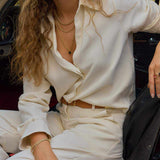 Woman wearing Cape Cod Horizon Necklace with London Blue Topaz pendant in 14k gold setting and matching gold chains with cream outfit seated in car interior